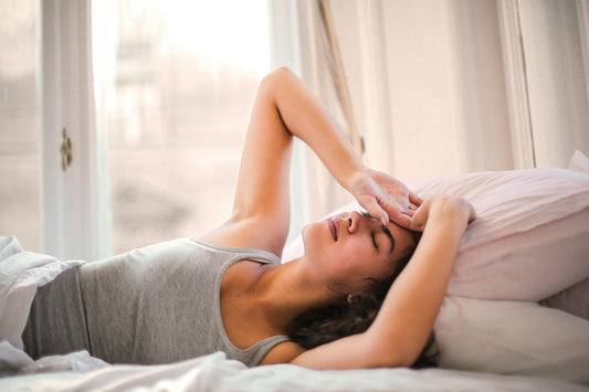 Woman in bed appearing restless or unsettled, illustrating the struggle to achieve deep, restorative sleep.