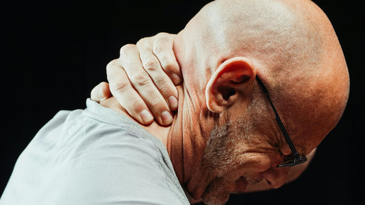 Man rubbing the back of his neck in discomfort, symbolizing neck pain from poor sleep posture
