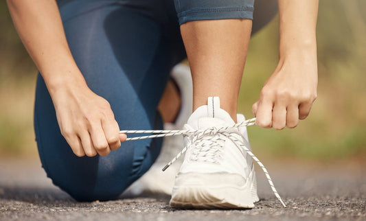 Woman tying running shoes before a walk, symbolizing the power of simple daily movement for long-term fitness, joint health, and consistent energy.