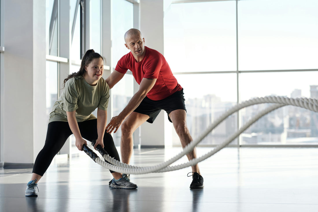 woman pushing through battle rope workout under trainer supervision—activating collagen through intense, load-bearing movement at the gym