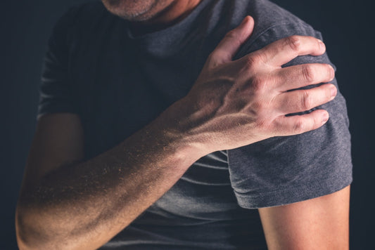 Man holding his shoulder in visible discomfort, reflecting symptoms of rotator cuff strain or irritation commonly caused by poor posture, overuse, or muscle imbalance.