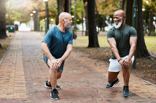 Older men performing dynamic lunges before exercise, activating muscles, improving joint mobility, and reducing injury risk as part of an effective warm-up routine.