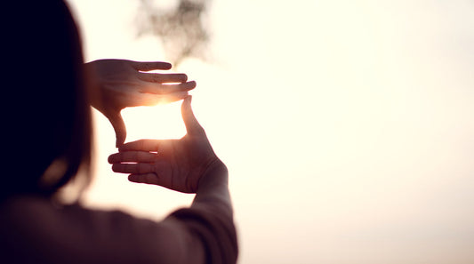 Hands framing the sun against a bright sky, symbolizing focused vision, future possibility, and the power of hope to guide daily health choices.