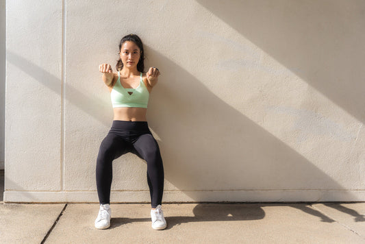 Woman holding a wall sit to build knee stability through isometric training and muscular control.