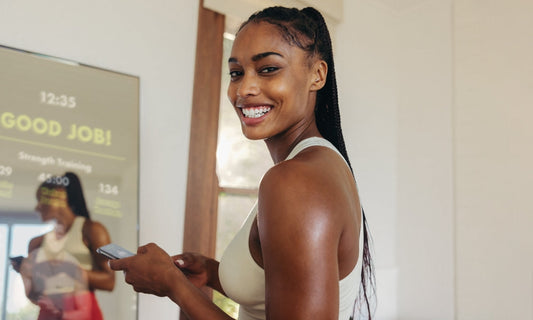 Woman smiling after completing smart home gym workout on fitness mirror screen