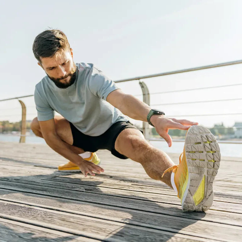 Man performing a deep hamstring stretch outdoors, demonstrating active recovery and mobility work